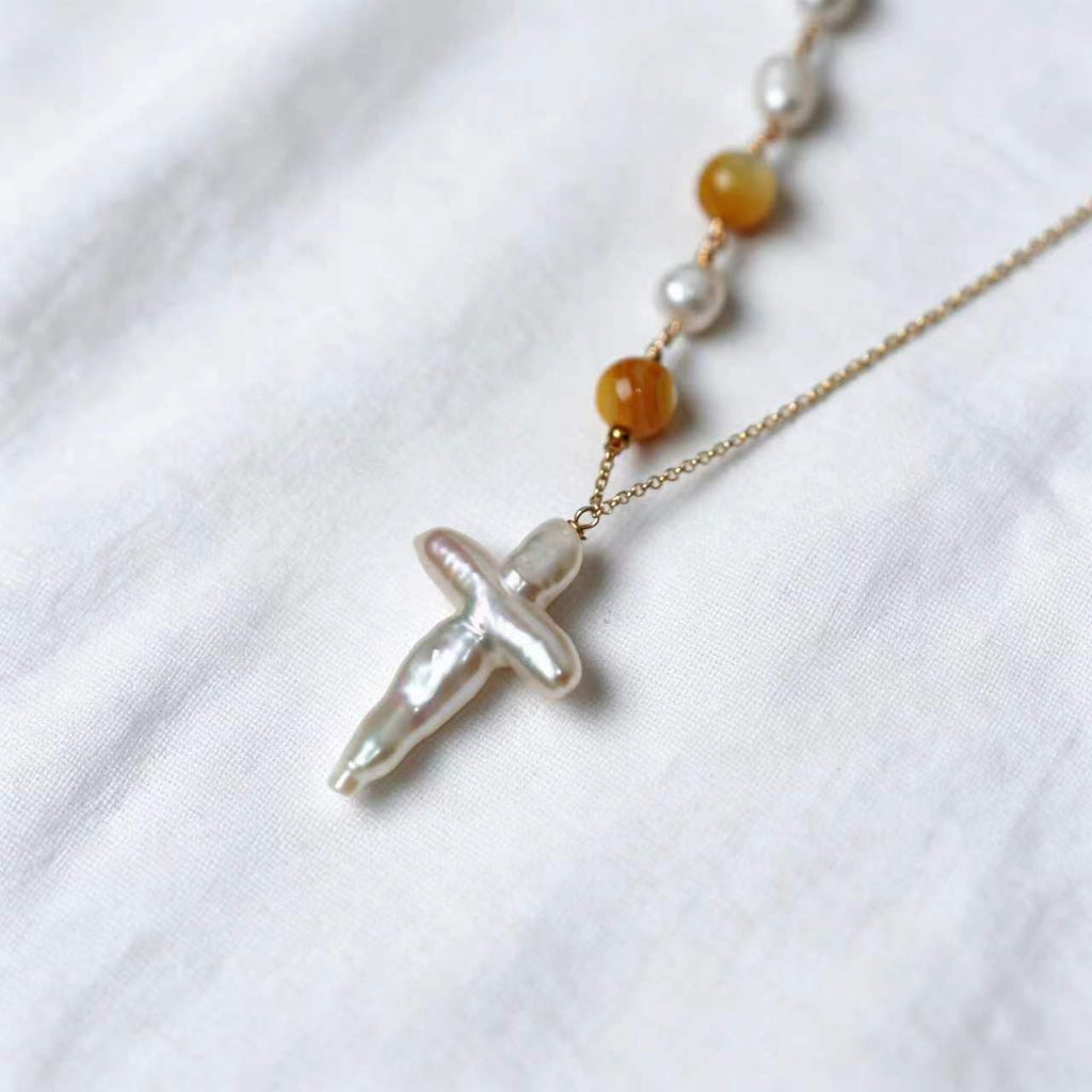 Close-up of the cross-shaped cultured freshwater baroque pearl pendant on the Aurelia Necklace