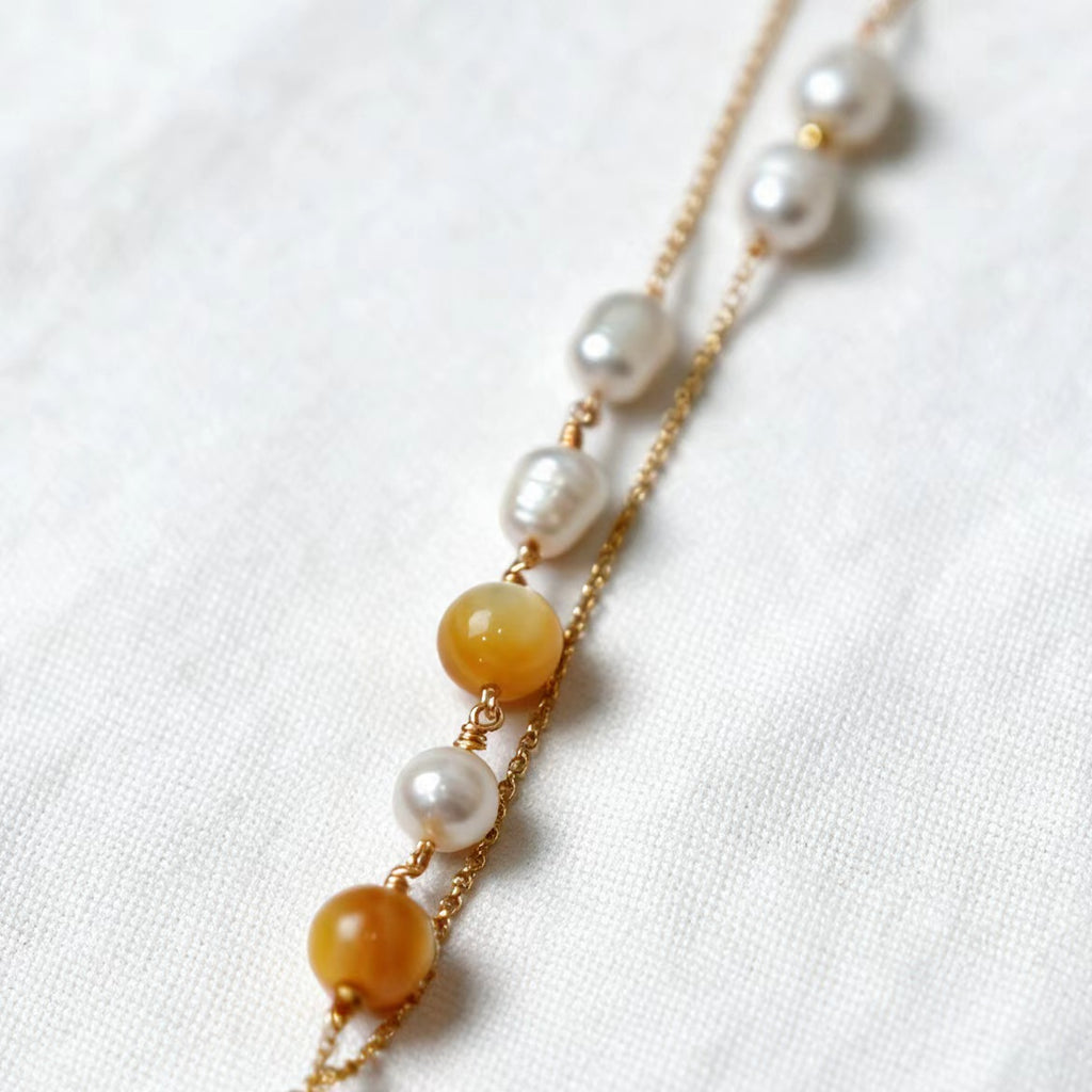 Asymmetrical freshwater pearl and golden-lip mother-of-pearl bead details on the Aurelia Necklace