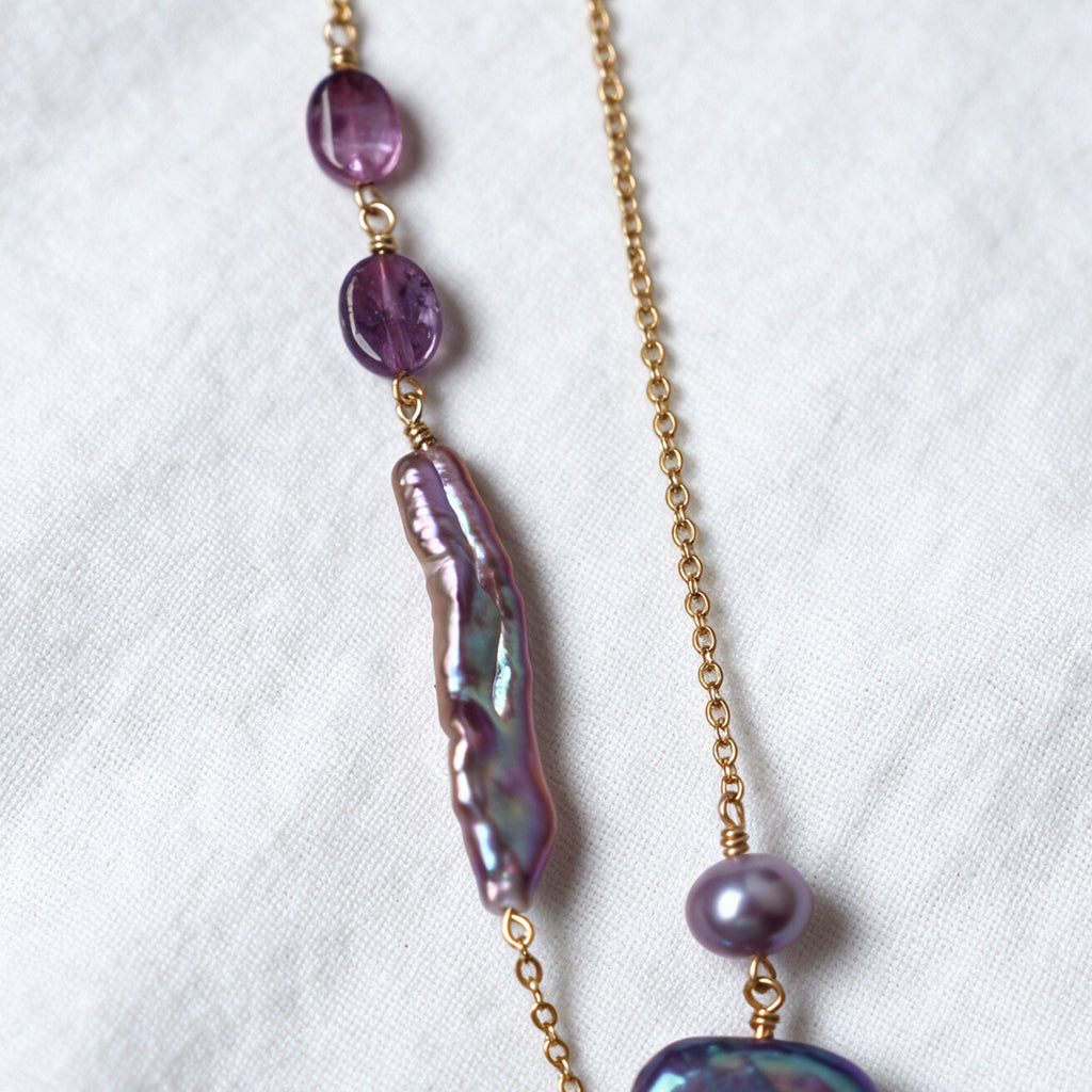 Purple tourmaline stones and an elongated iridescent baroque pearl on the Iris Necklace