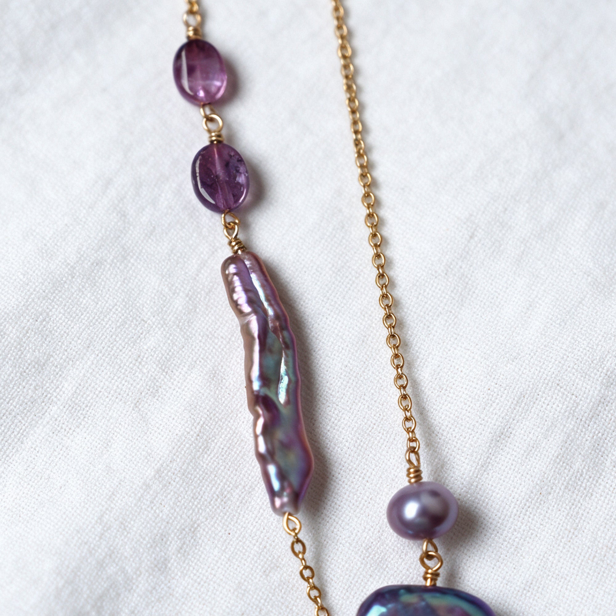 Purple tourmaline stones and an elongated iridescent baroque pearl on the Iris Necklace